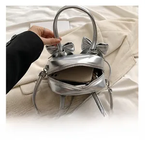 Detalle de bolso plateado con lazos mostrando el espacio interno para un móvil y su correa