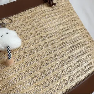 Detailed macro view of woven straw texture with brown leather trim and cloud charm