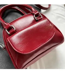 Dettaglio della borsa in pelle rosso scuro con fibbia argento e texture cerata