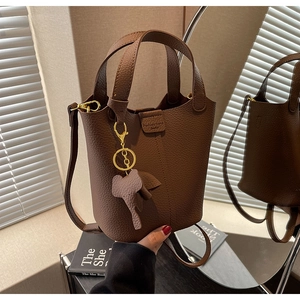 Detailed macro view of brown litchi pattern leather bucket bag with an elephant charm