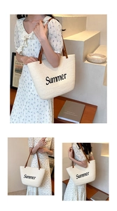 Detail of beige straw tote with Summer lettering and brown leather handles