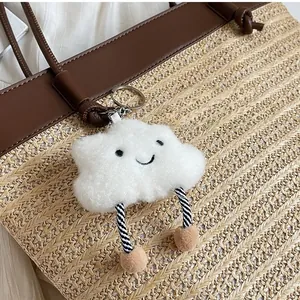 Detail of cute plush cloud charm with striped legs hanging on a woven tote bag