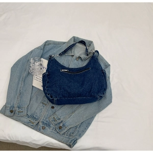 Détail du sac hobo en denim bleu foncé avec poches zippées et bandoulière réglable