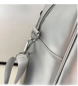 Detailed macro view of silver metallic bag hardware with zipper and white textile strap