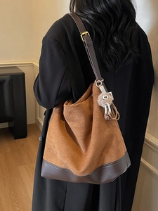 Retro caramel suede bucket tote bag with leather trim and plush charm worn by a model