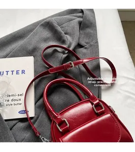 Dettaglio della fibbia d'argento regolabile su borsa in pelle bordeaux con tracolla rimovibile