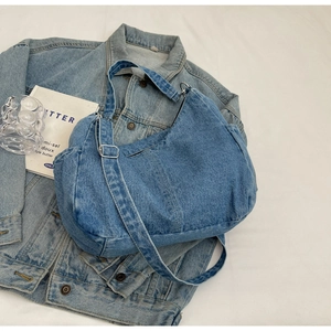 Détail du sac à bandoulière en denim bleu clair avec boucle argentée et sangle ajustable