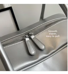 Close-up of smooth two-way zippers on metallic silver tote bag with leather pulls