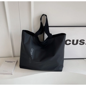 Detail of minimalist black nylon tote bag with gray text and durable wide strap handles