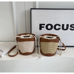Detailed view of straw bucket bag featuring leather trim and cotton drawstring closure