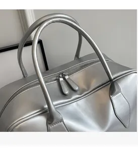 Detail of silver metallic tote bag featuring double zippers and padded round handles