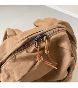 Detail view of the smooth dual zipper design with woven pullers on a brown backpack