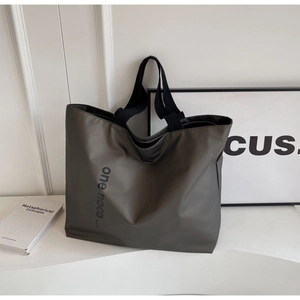 Detail of olive green nylon tote bag with wide black shoulder strap and letter printing