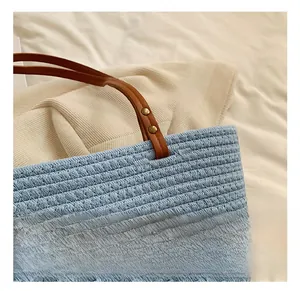 Detail showing blue woven straw texture and brown leather handle with gold rivets