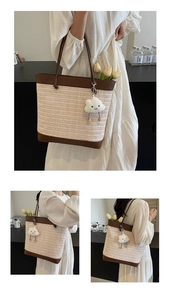 Detail of a large straw tote bag with brown leather handles and a white cloud plush charm
