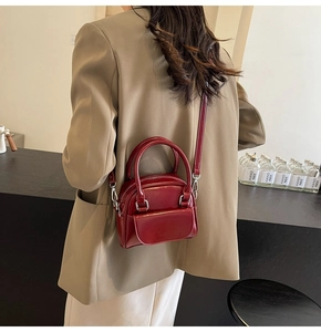 Dettaglio della borsa in pelle verniciata bordeaux con tracolla a catena su modella