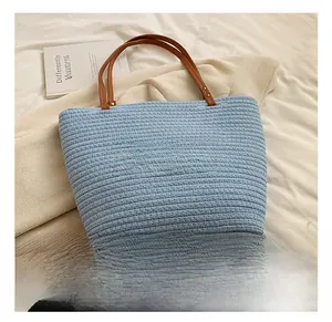 Detail of light blue straw tote bag featuring Summer embroidery and leather handles