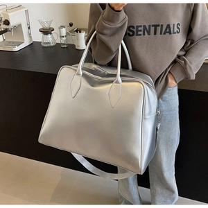 Silver metallic tote bag with reinforced handles and wide strap in an urban cafe setting