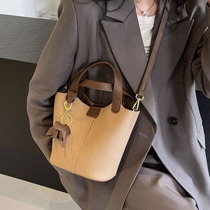 Chic beige and brown leather bucket bag with top handles and cute elephant charm