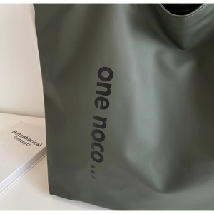 Detailed macro view of olive green waterproof nylon tote bag with minimalist lettering