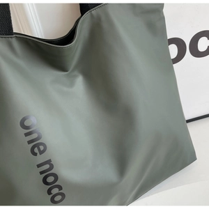 Close-up of olive green tote bag showing smooth matte texture and wide black shoulder strap