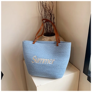 Detail of light blue straw tote bag with Summer embroidery and brown leather handles