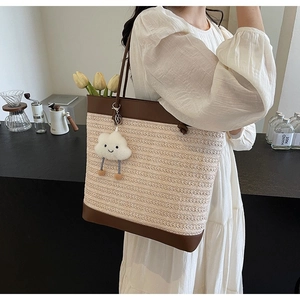 Detailed close-up of woven tote bag texture with brown leather trim and cloud charm