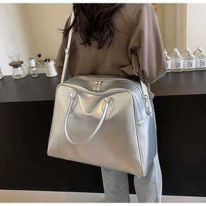 Detail of metallic silver tote bag featuring dual zippers and adjustable shoulder strap
