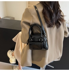 Dettaglio mini borsa a tracolla nera lucida con elegante manico superiore e sottile catena