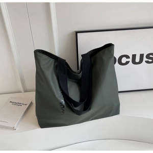 Close-up of olive green nylon tote bag with wide black straps and side lettering