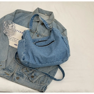 Vue détaillée du sac hobo en jean croissant avec poches zippées et bandoulière réglable