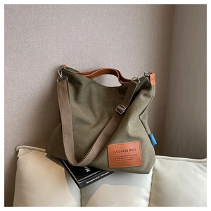 Detail of army green canvas tote bag showing the leather logo patch and texture