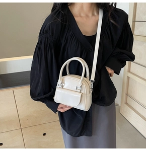 Borsa a tracolla minimalista bianco crema indossata da una modella in interni eleganti