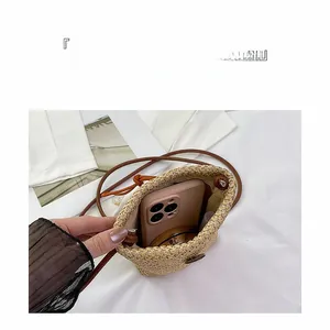 Straw mini bucket bag showing interior capacity with a brown leather shoulder strap