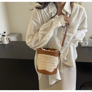 Detailed close-up of straw bucket bag with brown leather trim and drawstring closure