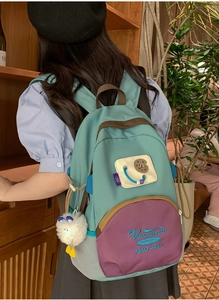 Close-up of sky blue and purple patchwork backpack with cute biscuit patch and plush ball