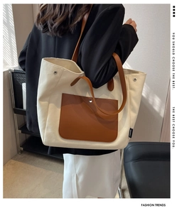 Detailed back view of a large canvas tote bag with brown leather pocket and strap
