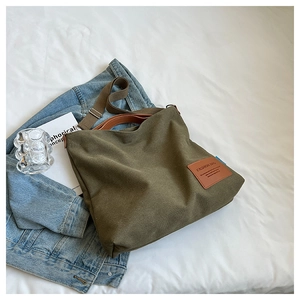 Detail of army green canvas tote with brown leather handles and adjustable shoulder strap