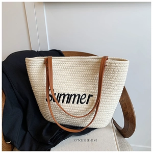 Close-up of cream woven tote bag with black Summer embroidery on a vintage chair