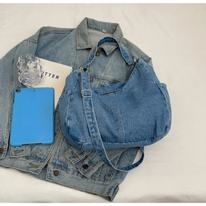 Détail du sac hobo en denim bleu avec bandoulière réglable et poche latérale sur blanc