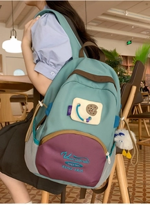 Close-up of mint green backpack with purple pocket, embroidery and cute duck pendant