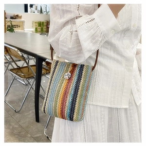 Detail of colorful woven straw bag with vintage round buckle and leather strap