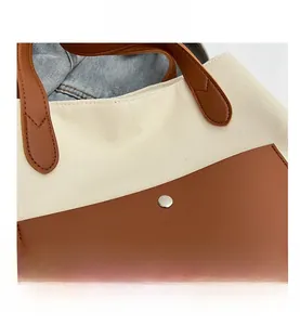 Close-up of canvas tote bag showing brown leather stitching and silver metal buckle detail