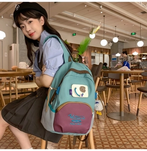 Close-up of a stylish color-block backpack with custom embroidery and cute plush pendant