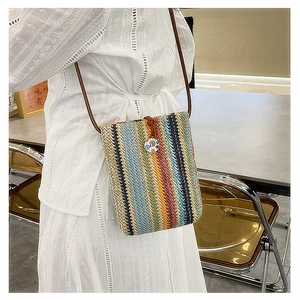 Detail of colorful woven straw crossbody bag with vintage button and slim brown strap