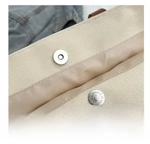 Detail shot of the strong magnetic buckle closure and durable canvas fabric on the tote bag