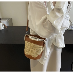Close-up of hand-woven straw bucket bag with brown leather trim and canvas drawstring