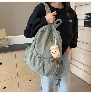 Close-up of olive green nylon backpack with large capacity and cute plush pendant