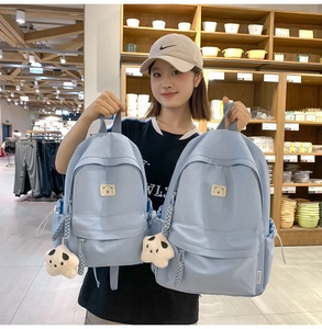 Detail view of light blue nylon backpack featuring a cute panda plush keychain and bear patch
