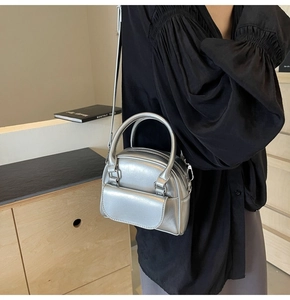 Dettaglio della mini borsa a mano argento metallizzato abbinata a camicia nera a pieghe